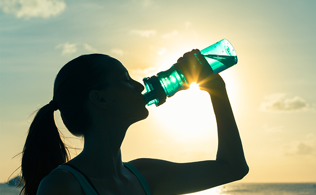 Woman drinking water at the beach in San Diego