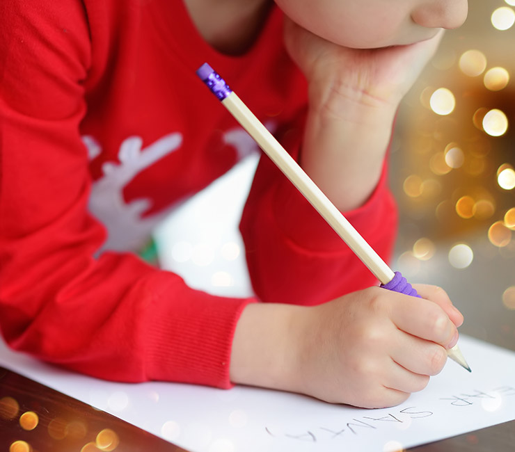 Child writing a letter to Santa at the Catamaran Resort Hotel's Santa’s Letter Station on their San Diego winter vacation